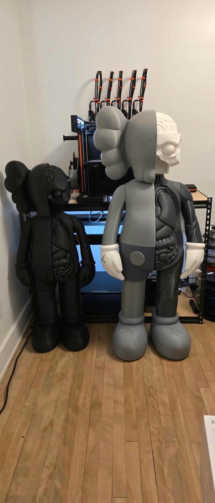 Deux KAWS anatomie devant les imprimantes 3D de l'atelier